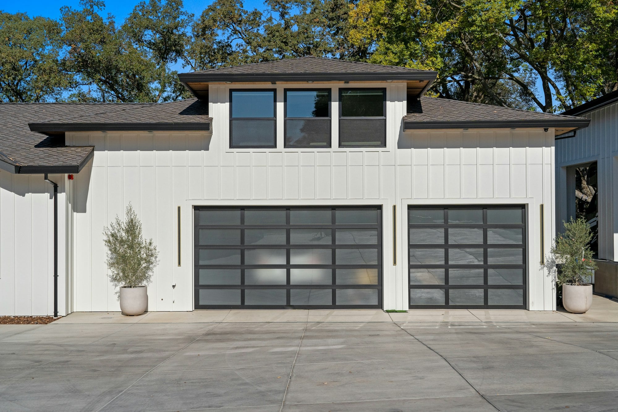White modern home with two dark glass-panel garage doors