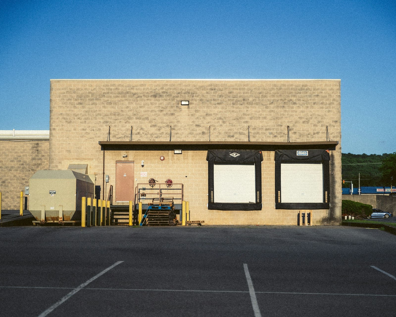 Two white roll-up dock doors on a block warehouse wall