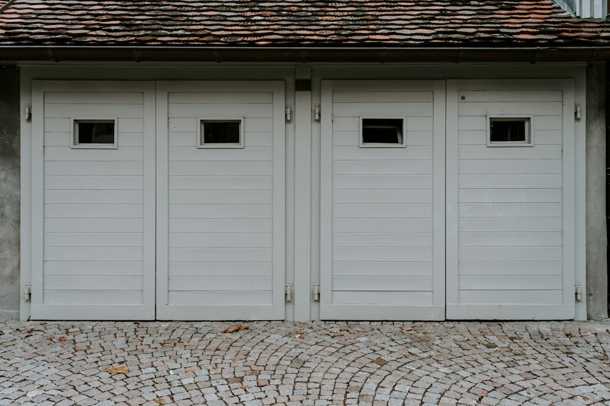 Pair of pale side-hinged garage doors with small windows